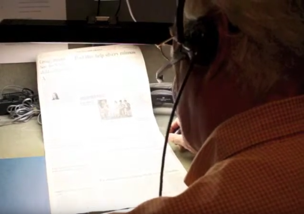 man transcribing newspaper into microphone